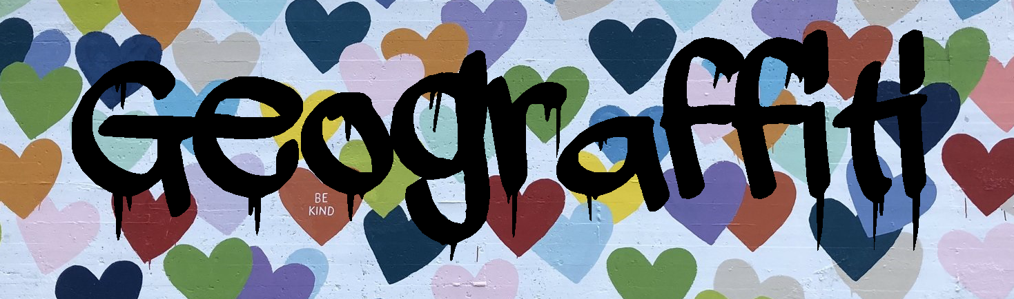 Geograffiti written on top of a brick wall painted white and covered in hearts of various colors